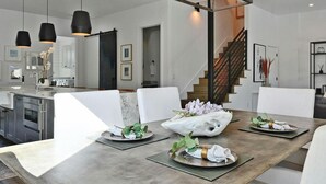 A modern dining area with a large rectangular table, white upholstered chairs, and a geometric metal chandelier. - Luxe Home in Iconic Zilker/ Barton Springs neighborhood- POOL (Austin)