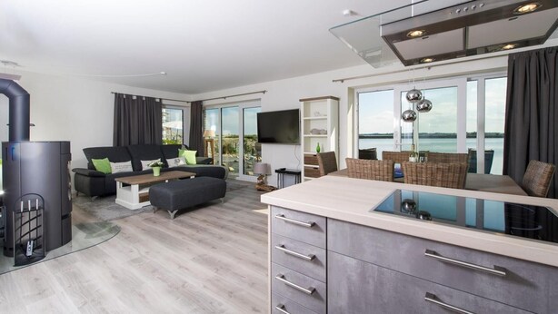 A modern living room with a sofa, TV, and a view of the sea. - Yachtblick auf der Ostsee (Olpenitz)