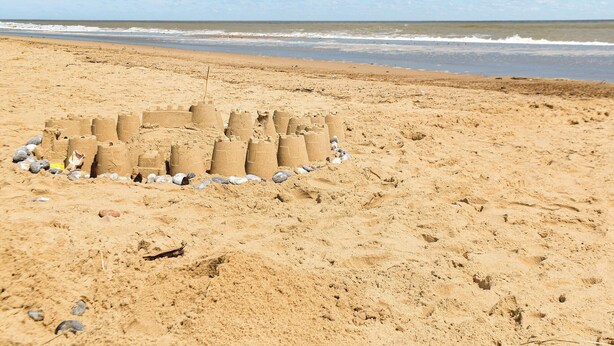 Una playa arenosa con una estructura de castillo de arena.