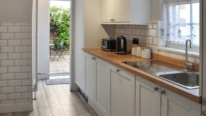 Una cocina con armarios blancos, encimera de madera, un lavabo y una ventana.
