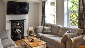 Una sala de estar con un sofá, una mesa de centro, una chimenea y un televisor montado en la pared.