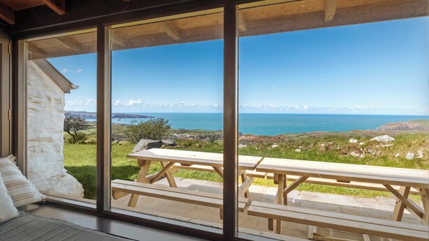 Una stanza con ampie finestre su un panorama suggestivo, soffitto in legno e vista mare.