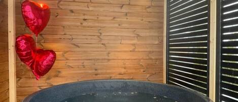 Un jacuzzi en una cabaña de madera con pared de madera y una ventana con persianas horizontales.