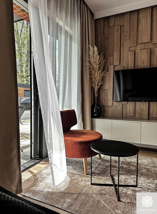 Relax in a spacious living room with a large window, comfortable armchair, and flat-screen TV.