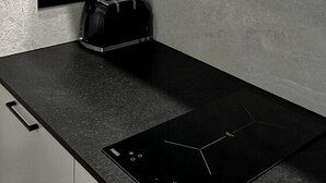 A kitchen with a black induction cooktop, a toaster, and a microwave. - Gościniec Warmiński by Elite4Rent (Stawiguda)