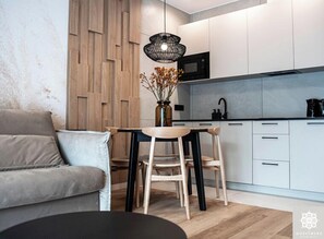 Cozy living space with a wooden accent wall, sleek pendant light, and modern dining area.