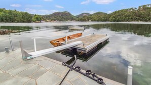 A dock with a wooden boat and a floating platform, surrounded by calm water and greenery.