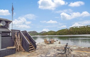 A dock with a staircase leading to a building, a table and chairs by the water, and a view of a forested hill. - Gorgeous home in Førde i Hordaland with WiFi (Førde i Hordaland)