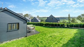 A residential area with a house featuring a deck and a well-maintained lawn. - Fair Isle Holiday Cottages - Fisher (Near Newport)