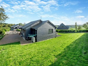 Een modern gebouw met een schuin dak, een verharde opgang en een gazon.