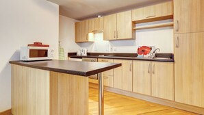 Une cuisine moderne dotée de meubles en bois, d’un four à micro-ondes, d’une bouilloire et d’un grille-pain escamotable.