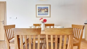 Un coin repas avec une table et des chaises en bois, un vase rempli de fleurs et un tableau encadré accroché au mur.