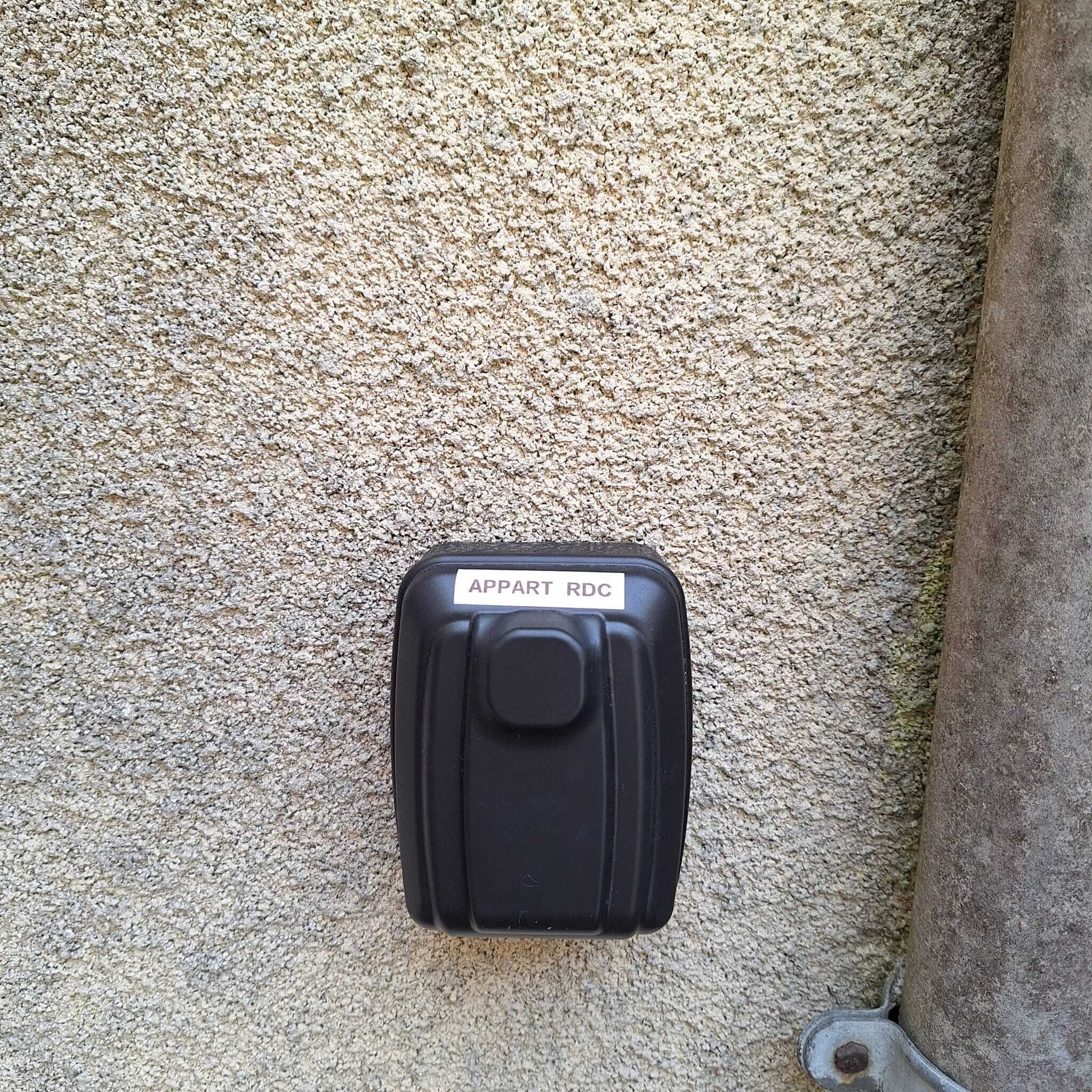 A black intercom with a label reading "APPART RDC" mounted on a textured wall.