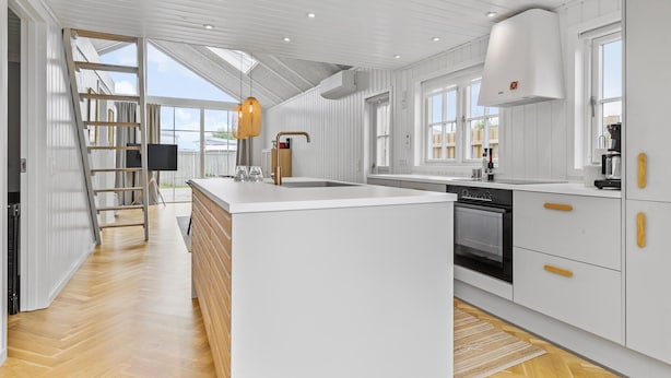 Una cocina moderna con una isla central, armarios blancos y un amplio ventanal que proporciona luz natural.