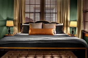 A bed with a headboard, multiple pillows, a blanket, and two bedside tables with lamps.