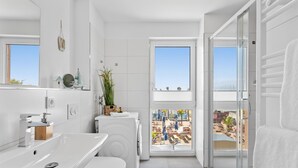 Et moderne badeværelse med et stort vindue, en vask, toilet og bruseområde.