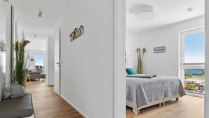 Et moderne soveværelse med et stort vindue, en seng, et natbord og udsigt til det fri.