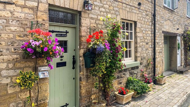 A stone building with a green door labeled "LUMLEY COTTAGE."