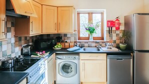 A modern kitchen with wooden cabinets, a built-in oven, a dishwasher, and a refrigerator. - 2 bedroom accommodation in Gower (Gower)