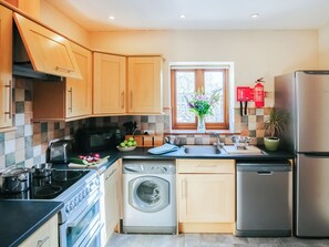 Une cuisine moderne avec des meubles en bois, un four encastré, un lave-vaisselle et un réfrigérateur.