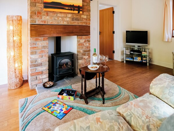 A living room with a brick fireplace, a television, and a cozy seating area.