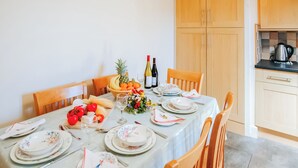 A dining table set with plates, cutlery, a fruit bowl, and a wine bottle. - 2 bedroom accommodation in Gower (Gower)