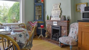 Un coin repas avec une table dressée pour quatre personnes, une cheminée et un meuble contenant des objets décoratifs.