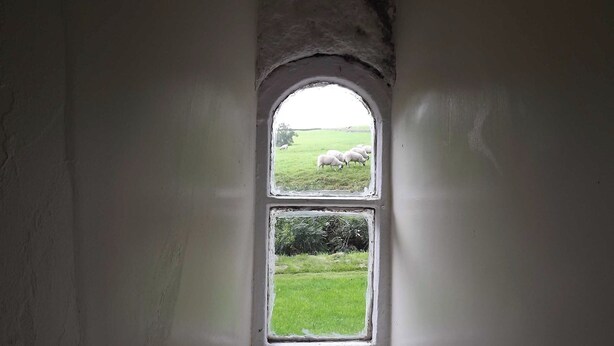 A narrow, arched window with a view of a grassy field and sheep. - A real ’Escape to the Country’ in truly welcoming surroundings. (Askrigg)