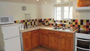 A kitchen with wooden cabinets, a microwave, a sink, and a stove. - A real ’Escape to the Country’ in truly welcoming surroundings. (Askrigg)