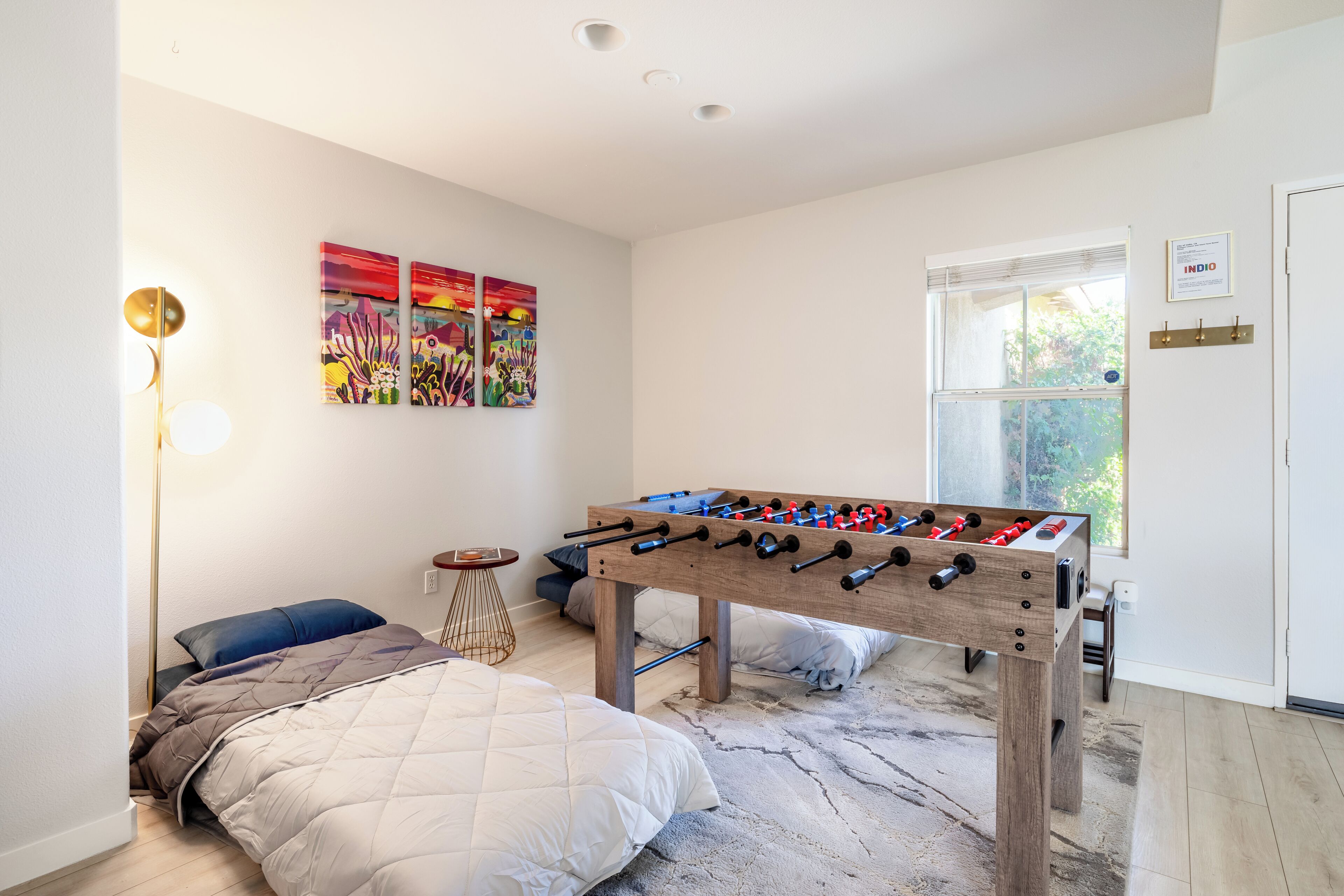 A modern bedroom with a bed, a foosball table, and artwork on the wall.
