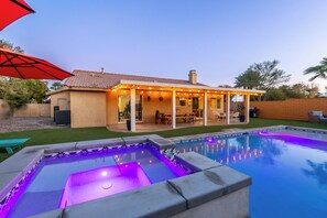 Ein Garten mit Swimmingpool, einer überdachten Terrasse und einem roten Sonnenschirm.