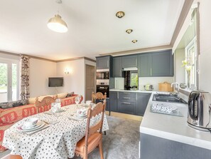 A modern kitchen with grey cabinets, a dining area with a table set for two, and a built-in oven.