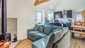 A cozy living room with a sofa, a fireplace, and a kitchen in the background.