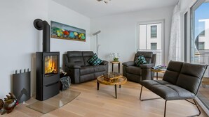 Een moderne woonkamer met een open haard, leren banken, een salontafel en een groot raam met uitzicht.
