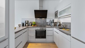 Een moderne keuken met witte kastjes, een Bosch oven, een koffiezetapparaat en een magnetron.