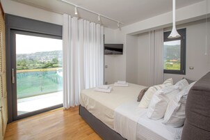 Un dormitorio moderno con una cama grande, un televisor montado en la pared y un balcón con vistas al campo.