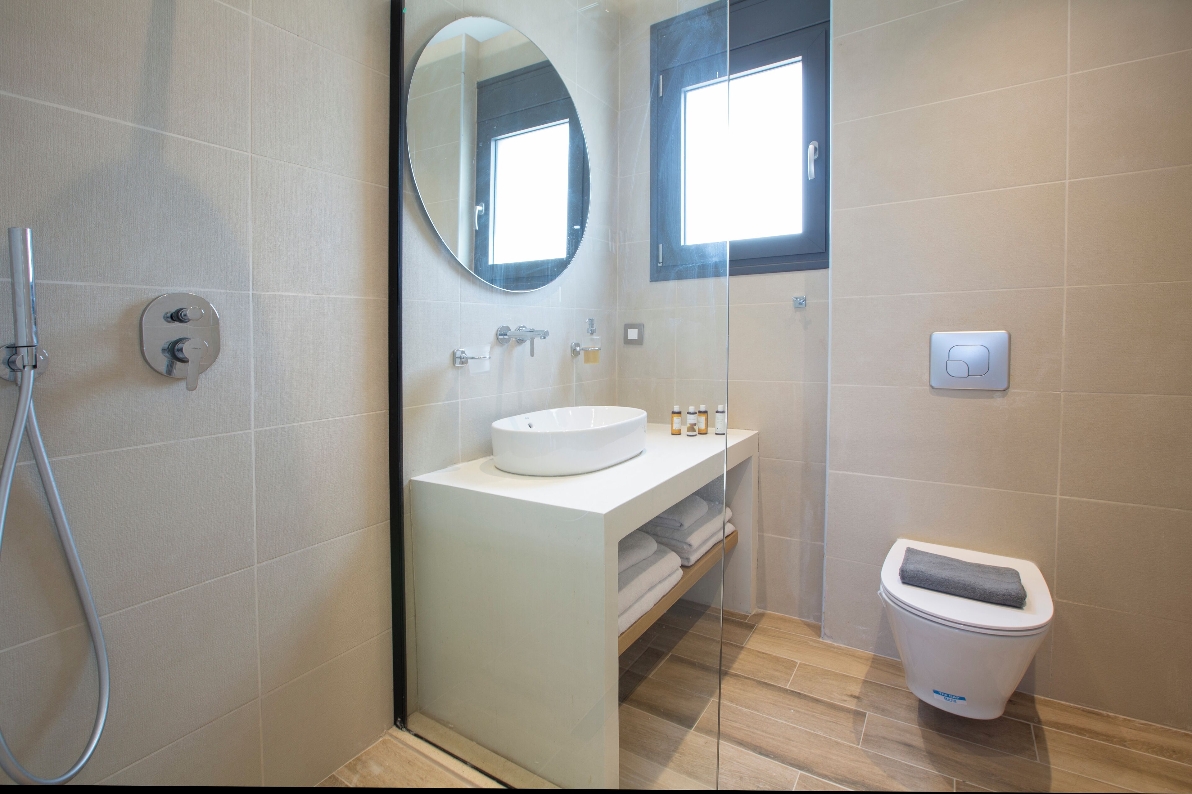 Une salle de bain moderne avec une douche à parois de verre, un lavabo blanc, un miroir et des toilettes.