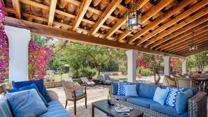 A covered outdoor seating area with a wooden ceiling, blue sofas, and a stone-tiled floor. - VILLA CAN TEULADA (Puerto Pollensa)
