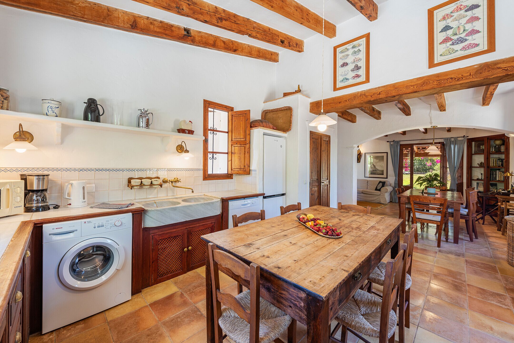 Una cocina amplia con una mesa de madera, lavadora y comedor con sillas.