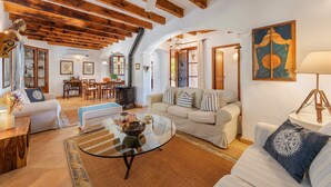 A spacious living area with a high ceiling, wooden beams, a glass coffee table, and a cozy seating arrangement. - VILLA CAN TEULADA (Puerto Pollensa)