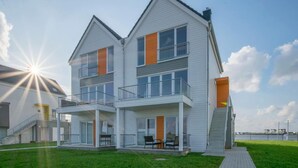 A two-story residential building with a balcony, large windows, and a view of the water. - Beautiful apartment in Olpenitz (Olpenitz)