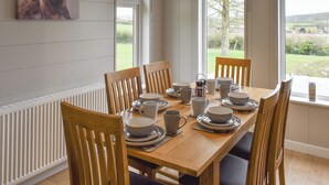 A dining room with a wooden table set for six, surrounded by six wooden chairs.