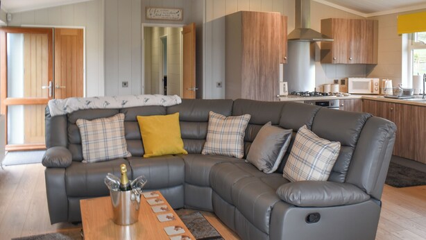 A modern living room with a grey sectional sofa, a wooden coffee table, and a yellow throw pillow.