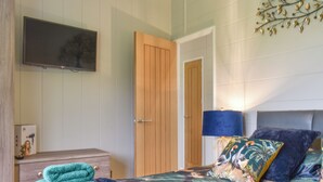 A bedroom with a bed, a TV, a wooden door, and a wall-mounted decoration.