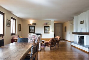 Un coin repas avec une table et des chaises en bois, une cheminée et des tableaux encadrés accrochés aux murs.