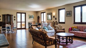 A spacious living room with a wooden coffee table, a sofa, and a patterned armchair. - La grande Valsassina - Salone (Pasturo)