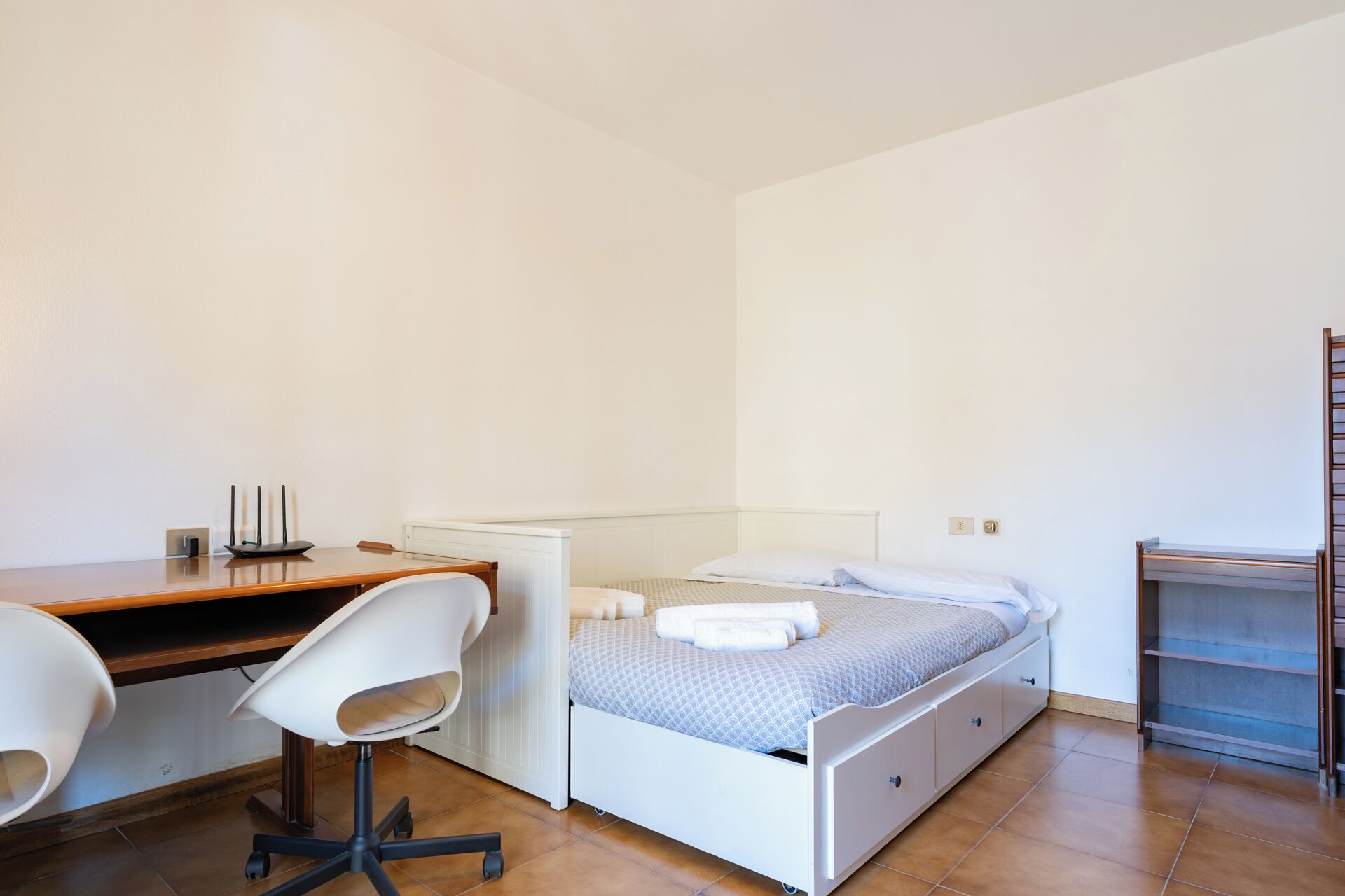 A bedroom with a bed, a desk, a chair, and a radiator.