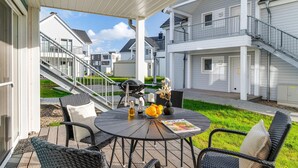 A covered patio with a round table, wicker chairs, and a grill. - Lovely apartment in Olpenitz with sauna (Olpenitz)