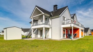 A two-story house with a balcony, a covered porch, and a small attached garage. - Beautiful apartment in Olpenitz (Olpenitz)