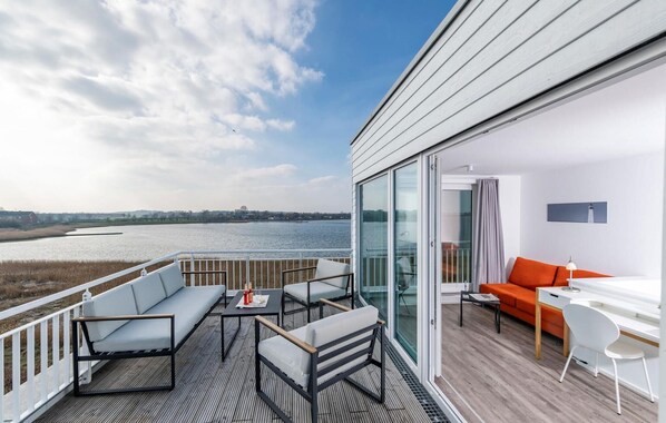 Enjoy a serene view of the water from this stylish balcony with a comfortable seating area.